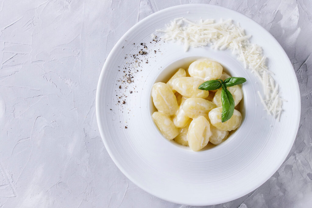 Cremige Gnocchi in Sahne-Parmesan-Sauce mit Basilikum und Parmesan im weißen Teller