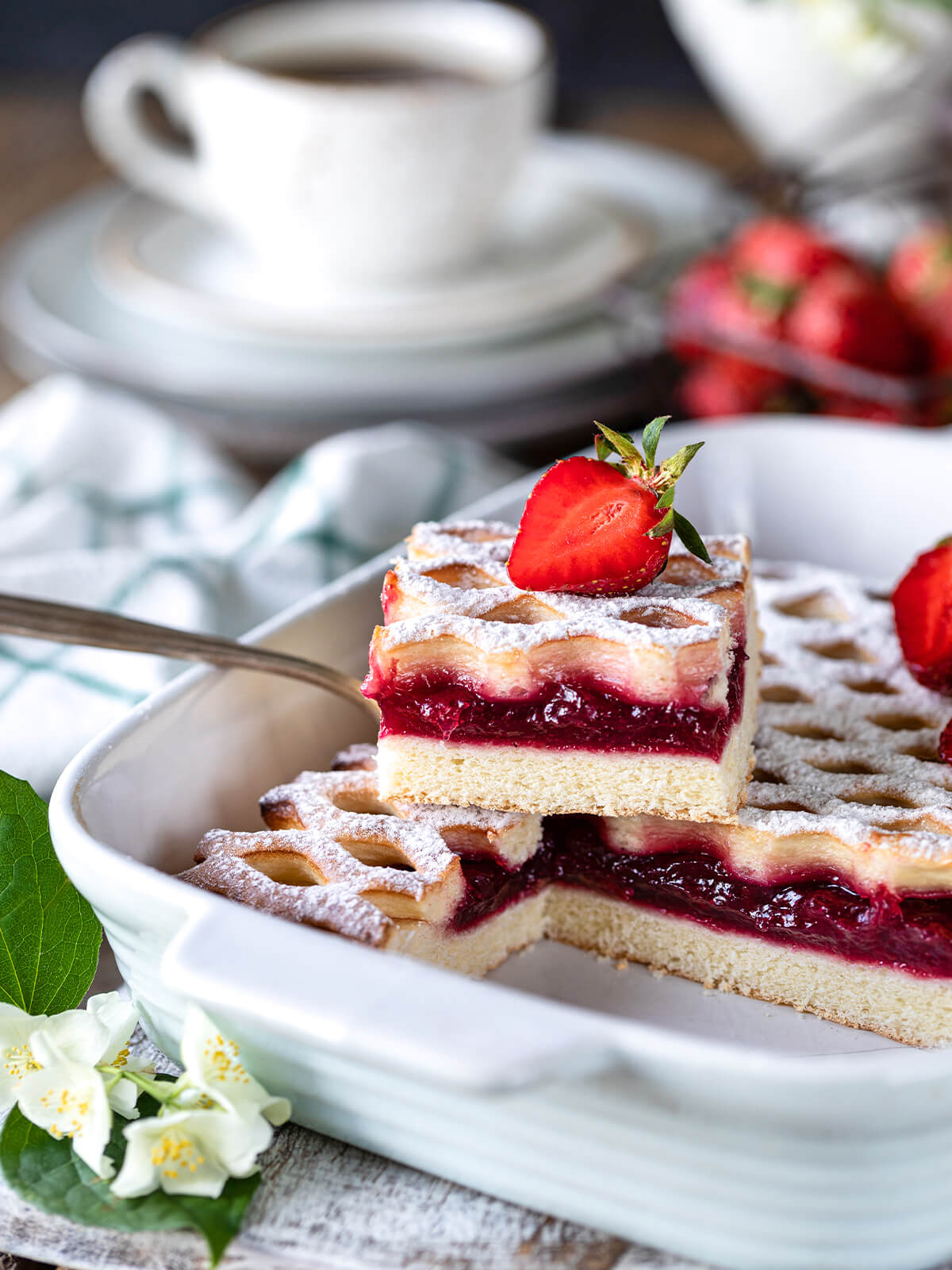 Angeschnittener Erdbeer-Gitterkuchen in der Form mit hellem Hefeteig-Boden und dicker dunkelroter Erdbeerschicht
