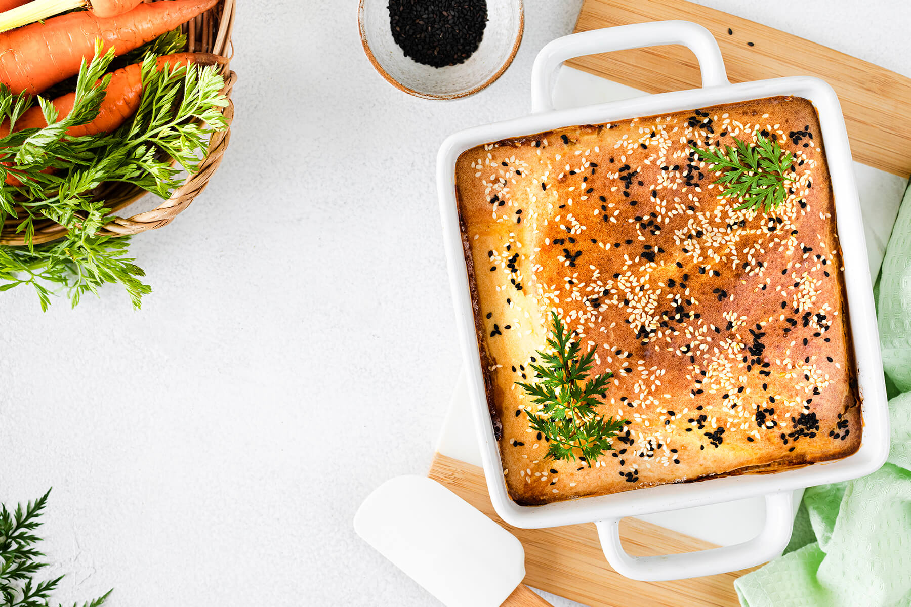 Herzhafter Schüttkuchen mit Kohl und Karotten ganz in der weißen Auflaufform mit Sesam und Schwarzkümmel