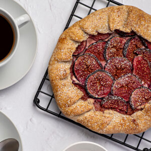 Feigen-Ricotta-Galette rustikal angeschnitten mit Kaffee und Honig