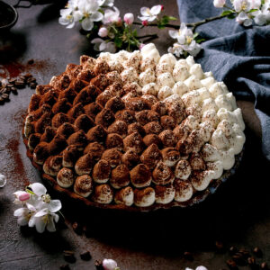 Glutenfreie Tiramisu-Torte mit dicht gespritzten Sahnetupfen, teils mit Kakao bestäubt