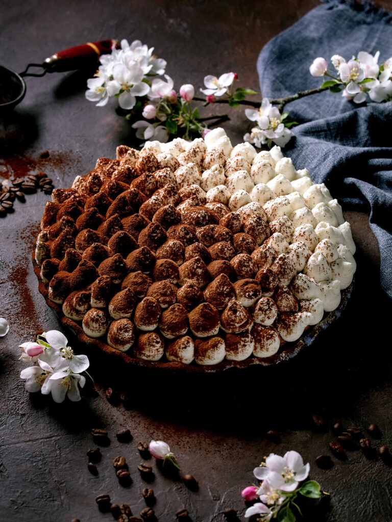Glutenfreie Tiramisu-Torte mit dicht gespritzten Sahnetupfen, teils mit Kakao bestäubt