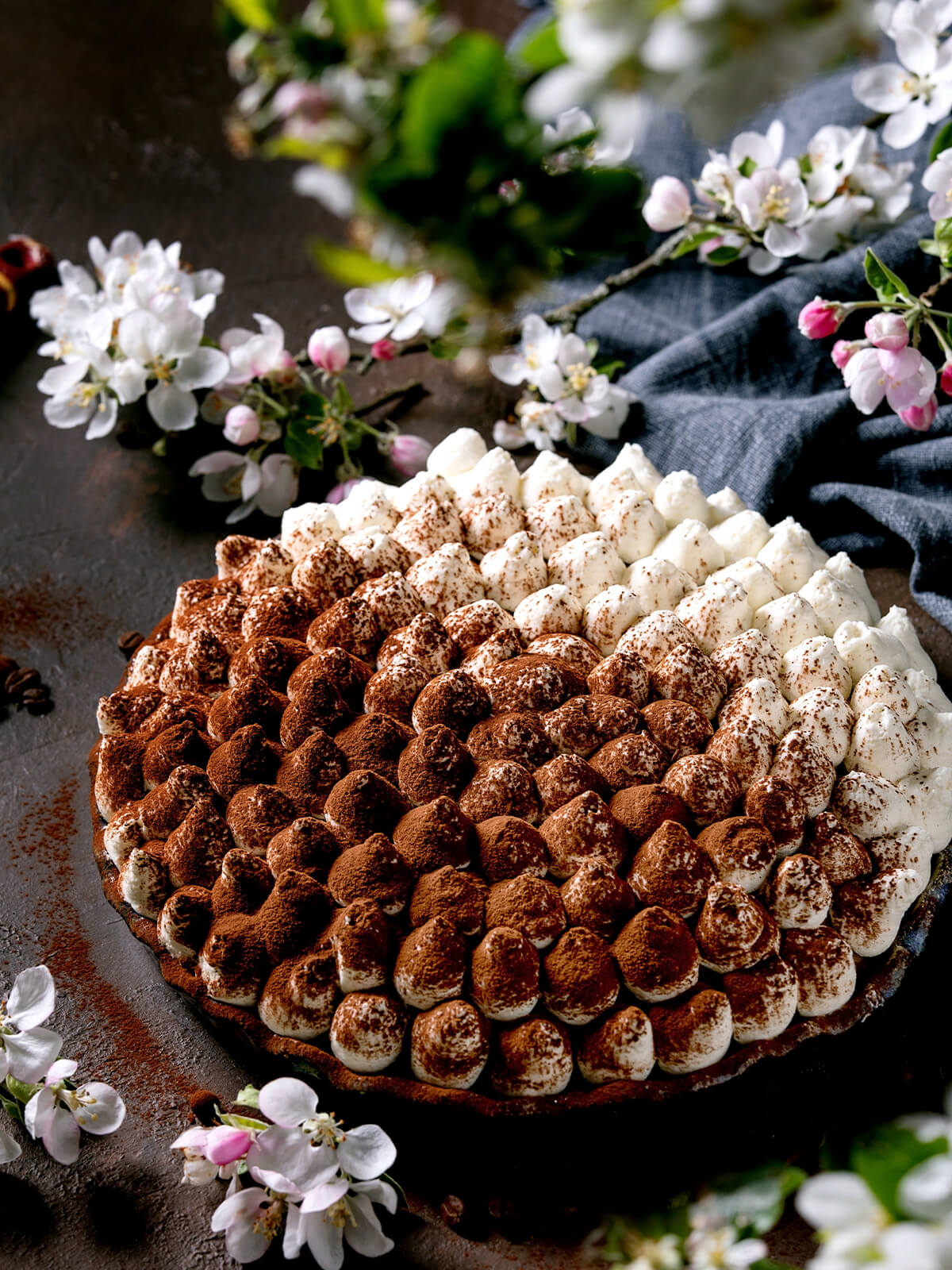 Glutenfreie Tiramisu-Torte mit dicht gespritzten Sahnetupfen, teils mit Kakao bestäubt