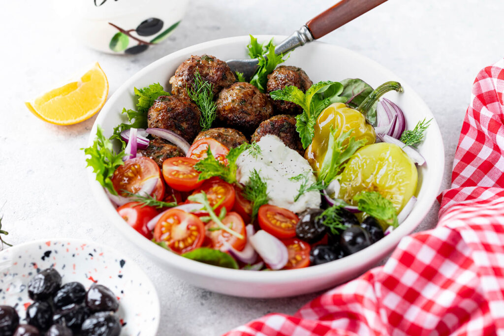Griechische Keftedes-Bowl mit Tzatziki, Paprika, Tomaten und Oliven