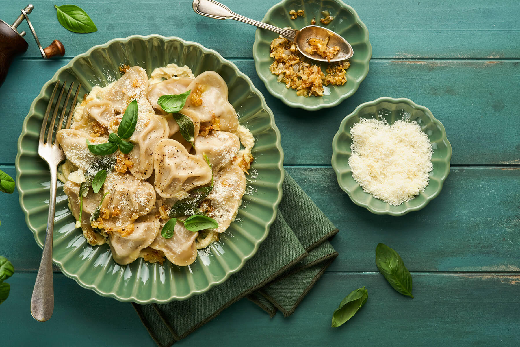 Herz-Ravioli mit Schälchen voll karamellisiertem Knoblauch und geriebenem Parmesan daneben