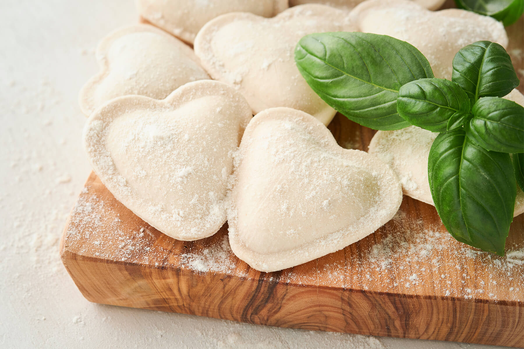Rohe, mit Mehl bestäubte herzförmige Ravioli auf einem Holzbrett