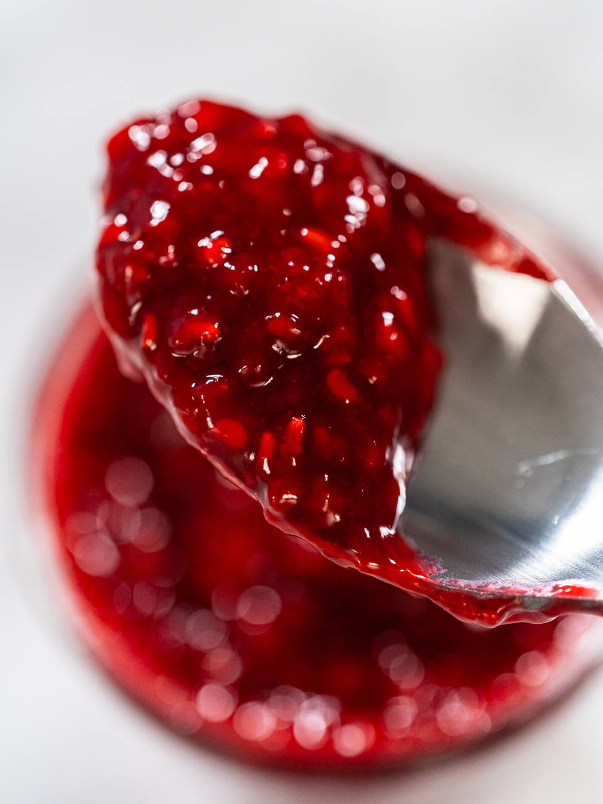 Löffel mit dicklicher roter Fruchtmasse über einem Glas, die Masse hält ihre Form