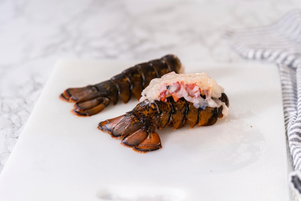 Butterflied Hummer-Schwanz mit auf den Panzer gehobenem Fleisch auf dem Schneidebrett