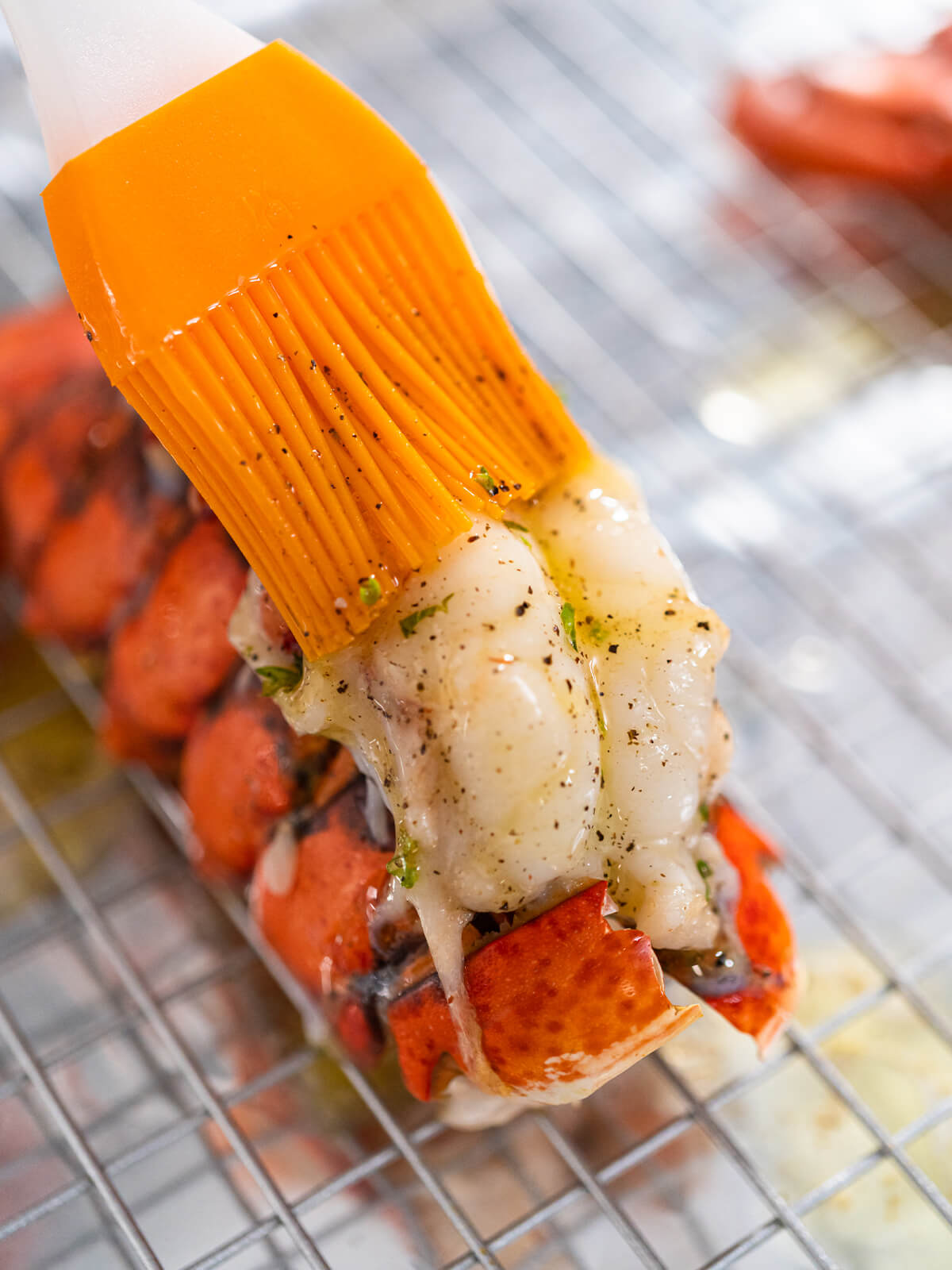 Hummer-Schwanz wird mit Knoblauch-Butter und Silikon-Pinsel bestrichen