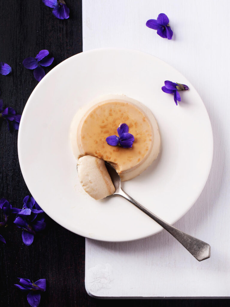 Gestürzte Karamell-Panna-Cotta mit frischen Veilchen-Blüten auf dem Teller
