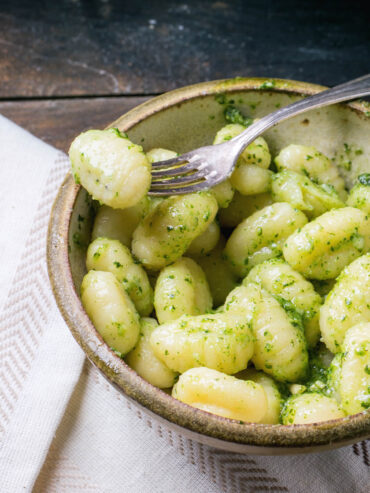 Kartoffel-Gnocchi mit Basilikum-Pesto in einer rustikalen Keramikschale mit Gabel