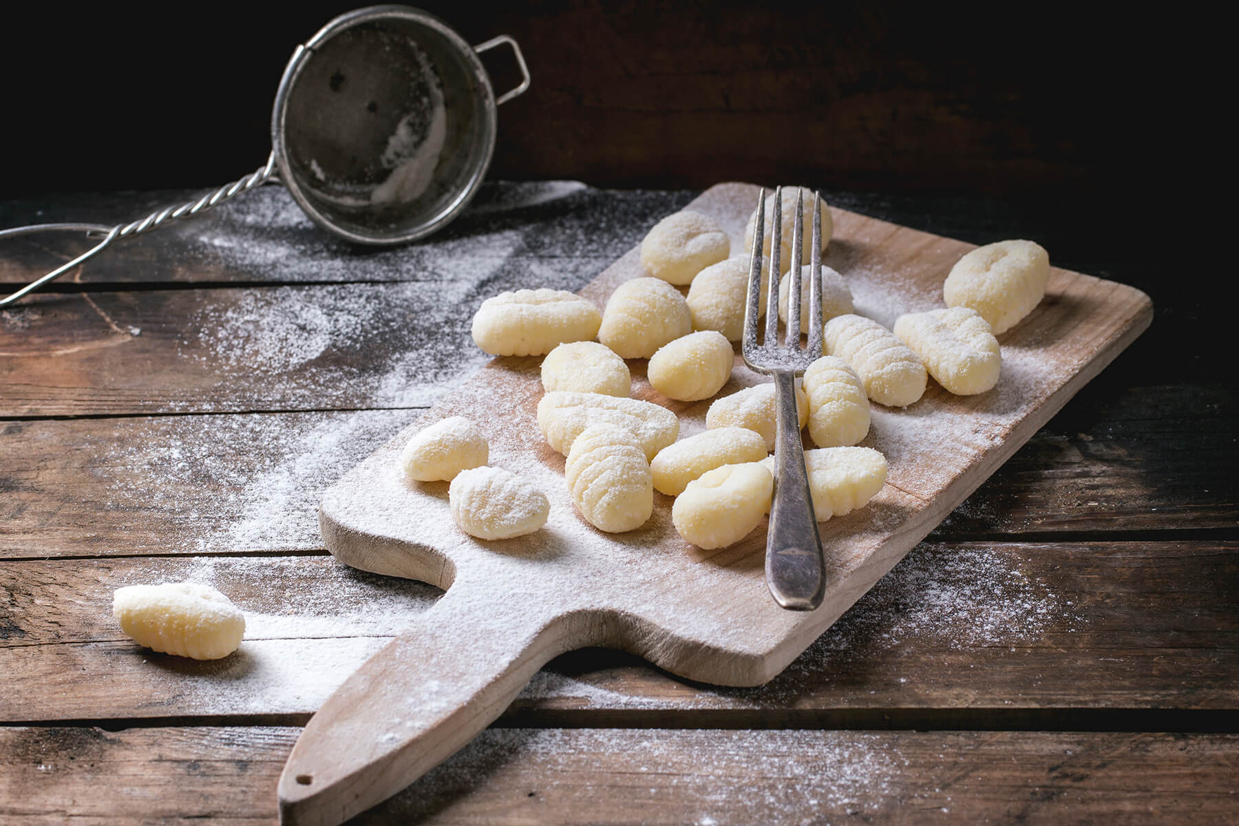 Frisch geformte Kartoffel-Gnocchi mit Gabelrillen auf einem bemehlten Holzbrett