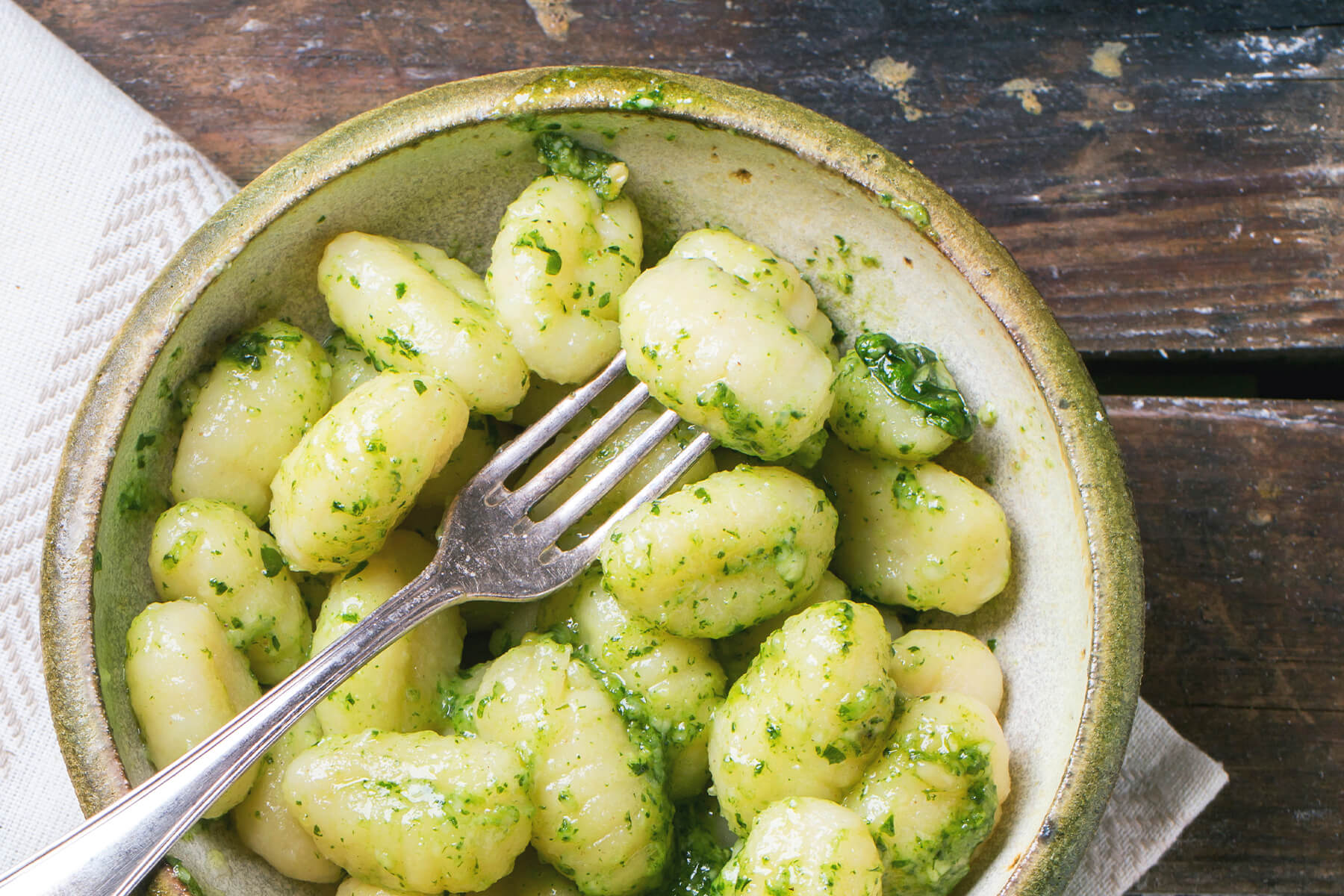 Fertige Kartoffel-Gnocchi mit grünem Basilikum-Pesto in einer Keramikschale mit Gabel