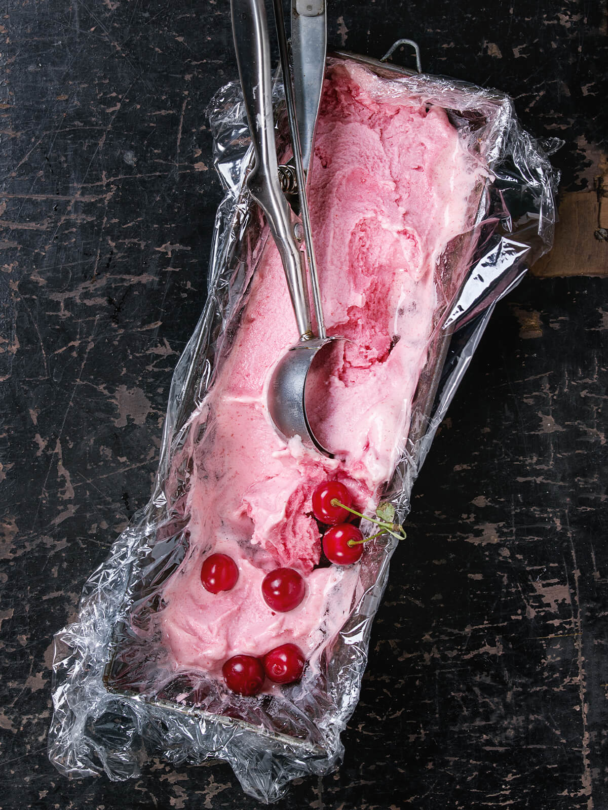 Scoopfähiges Kirsch-Sorbet mit eingedrücktem Eisportionierer und eingedrückten Kirschen