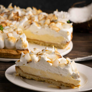 Stück Kokos-Sahne-Tarte im Querschnitt mit Mürbeteigboden, Kokoscreme und goldgebackenem Baiser