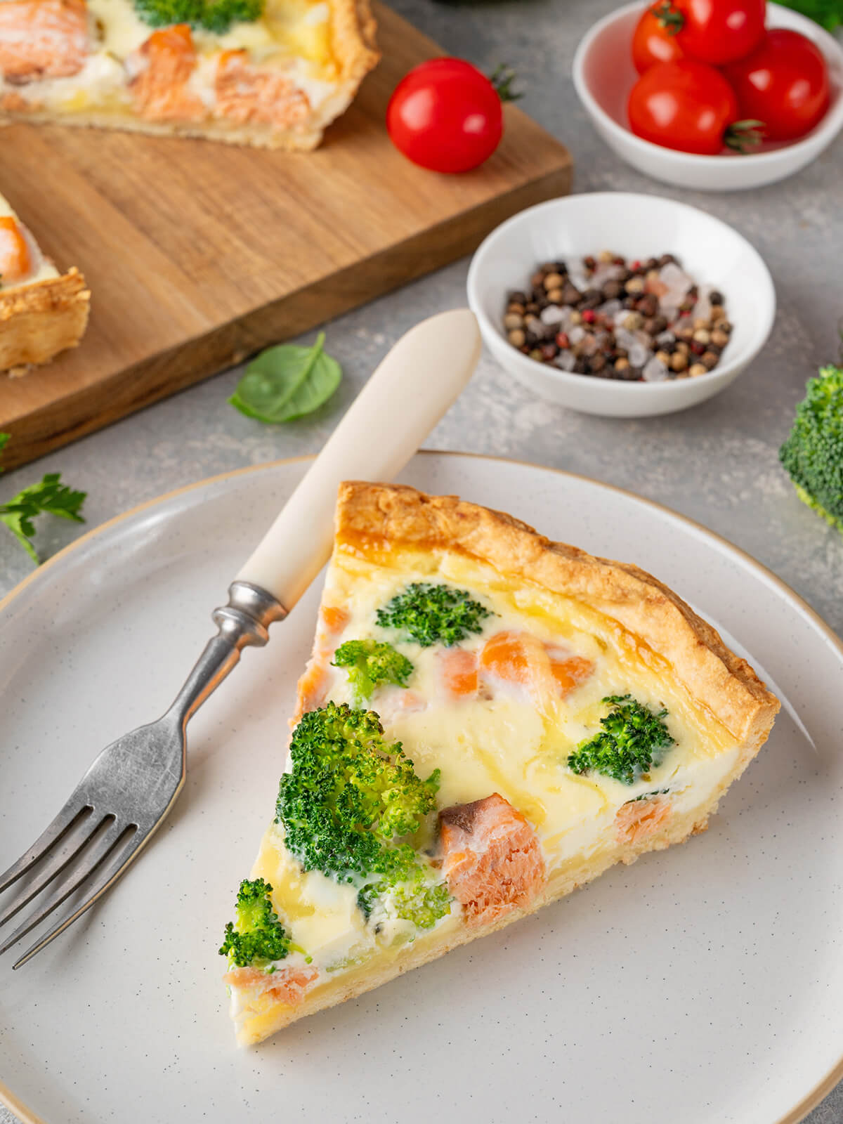 Angeschnittenes Stück Lachs-Brokkoli-Quiche auf einem Teller im Querschnitt