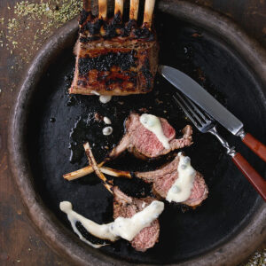 Gegrilltes Lammkarree mit dunkler Kruste, in Koteletts geschnitten mit rosa Mitte, nach Wunsch mit cremiger Kräutersauce