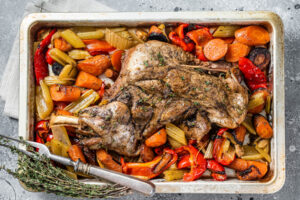 Lammschulter mit Wurzelgemüse von oben fotografiert – das ganze Blech mit Möhren, Sellerie, Paprika und Lammschulter darüber