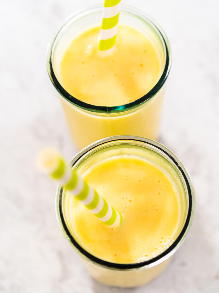 Zwei hohe Gläser cremiger Mango-Boba-Smoothie von oben, das satte Goldgelb leuchtet