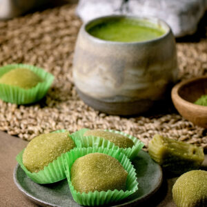Matcha-Mochi mit Matcha-Schokoladen-Ganache auf rosa Keramik mit Matcha-Tee