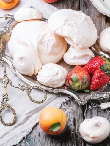 Klassische französische Meringue in drei Größen auf einem Silbertablett mit Erdbeeren