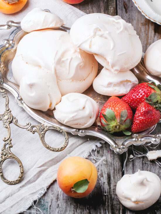 Klassische französische Meringue in drei Größen auf einem Silbertablett mit Erdbeeren