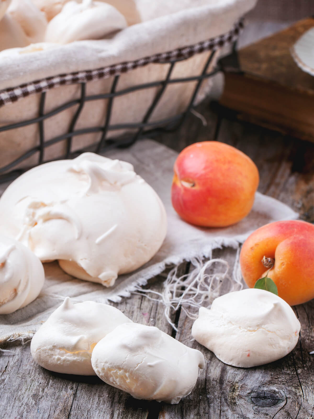 Französische Meringue mit halbierten und ganzen Aprikosen auf Leinen und Holz