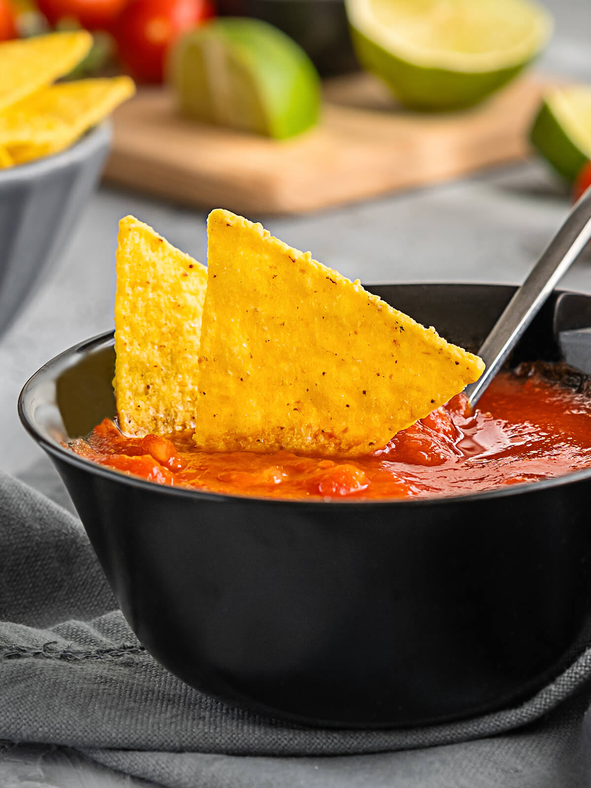 Mexikanischer Tomaten-Dip in dunkler Schale mit Tortilla-Chips