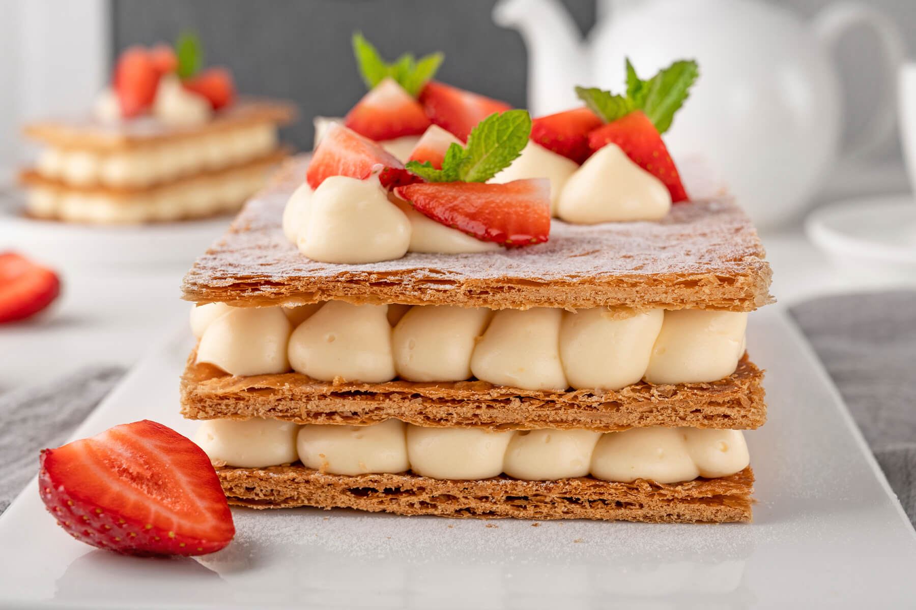 Mille-Feuille mit Creme-Tupfen, Erdbeerspalten und Minze obenauf