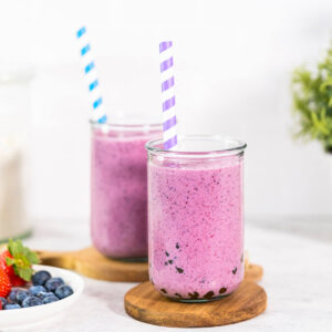 Zwei Gläser Mixed-Berry-Boba-Smoothie mit Tapioka-Perlen am Boden, daneben ein Tellerchen mit frischen Beeren