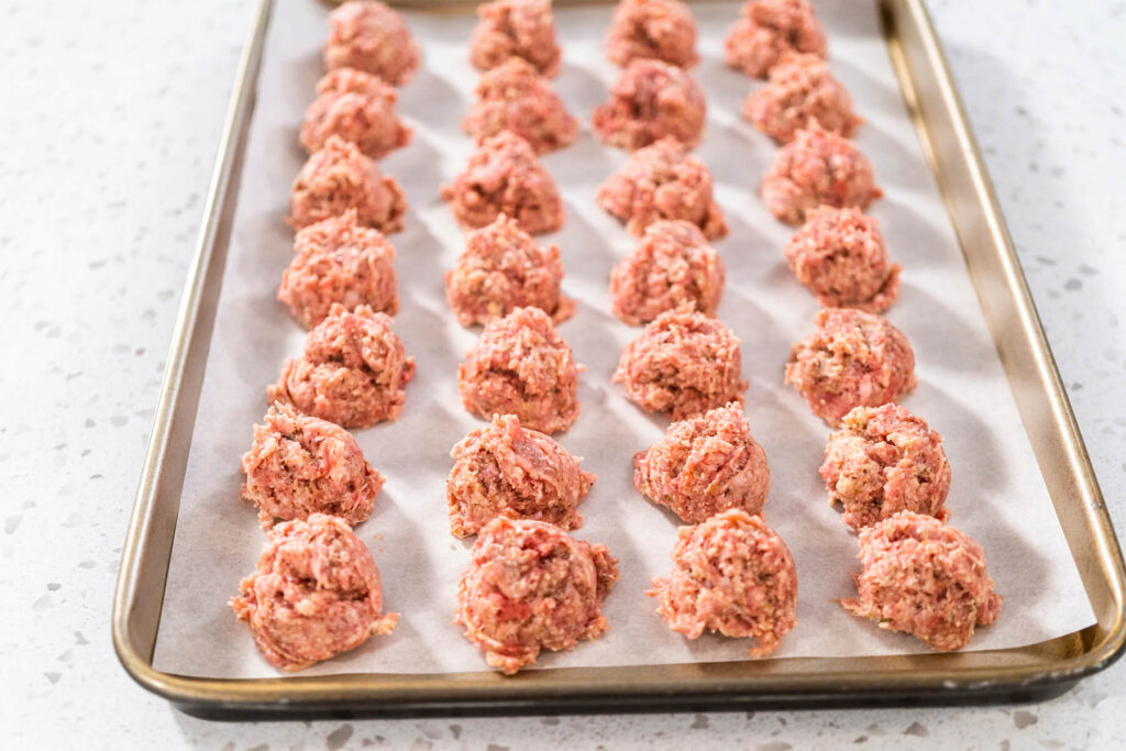 Backblech mit 28 roh portionierten Hackbällchen vor dem Backen von oben