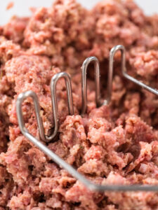 Hackmasse wird mit einem Kartoffelstampfer vermischt, Nahaufnahme