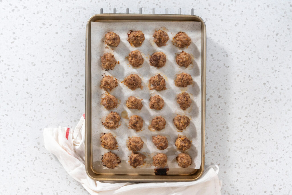 Backblech mit 28 fertig gebackenen Ofen-Hackbällchen von oben