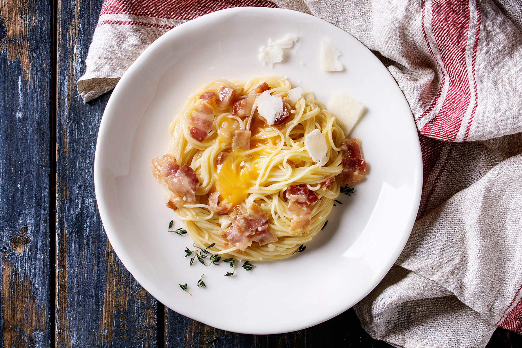 Fertige Pasta Carbonara von oben mit Pecorino-Spänen und schwarzem Pfeffer