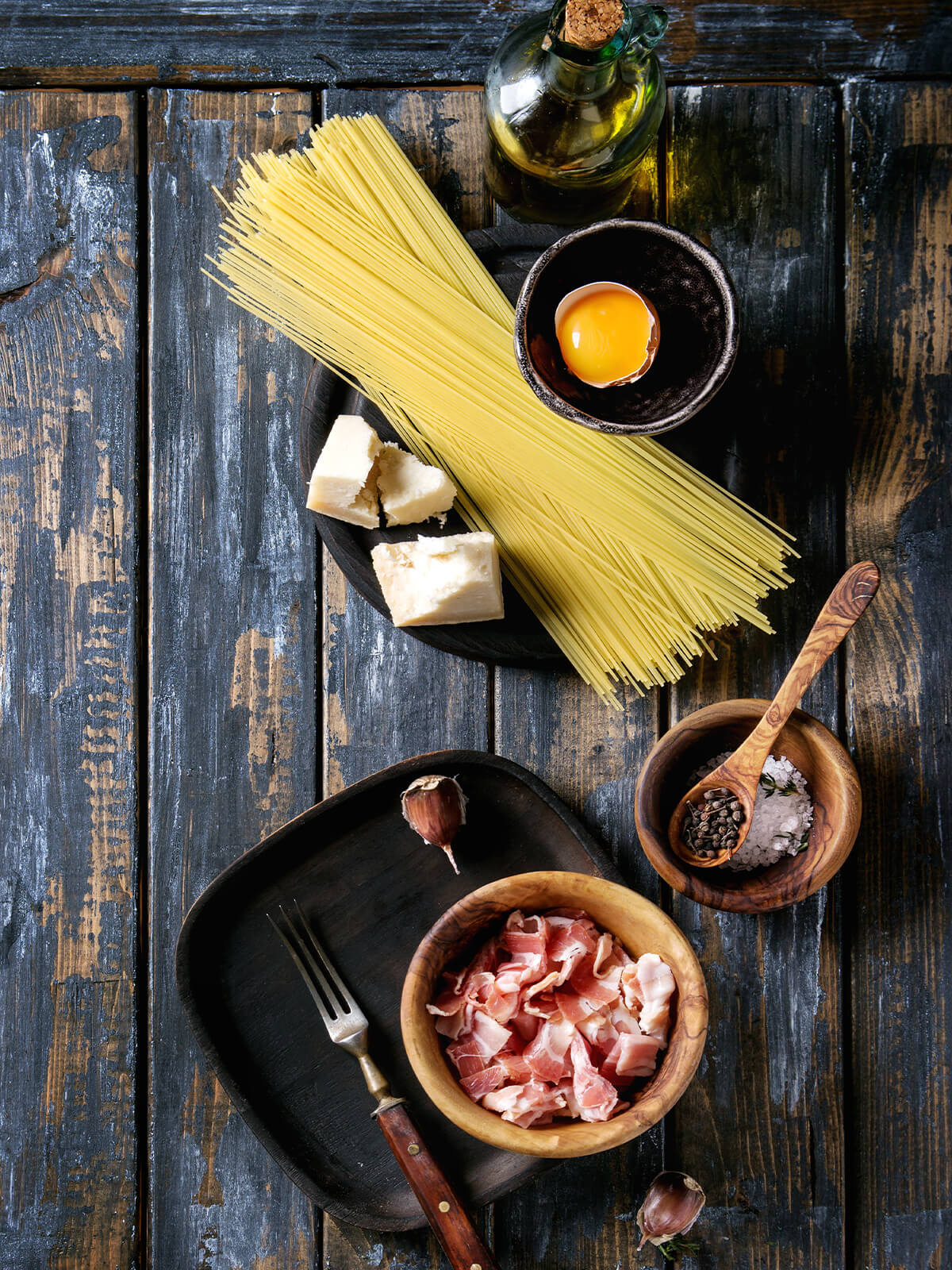 Zutaten für Pasta Carbonara – Pancetta, Käse, Eier und Pfeffer auf dem Tisch