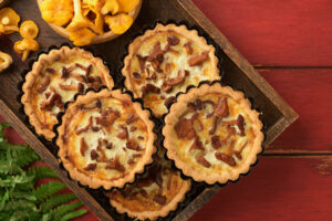 Pfifferling-Tartelettes in geriffelten Förmchen mit hellem Käse-Sahne-Guss und Pilzen obenauf