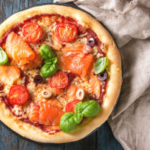 Pizza mit Tomatensauce, Mozzarella, Räucherlachs, Kirschtomaten und Oliven