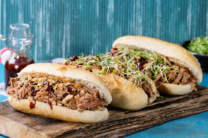 Drei Pulled Pork Subs mit verschiedenen Toppings auf einem Servierbrett