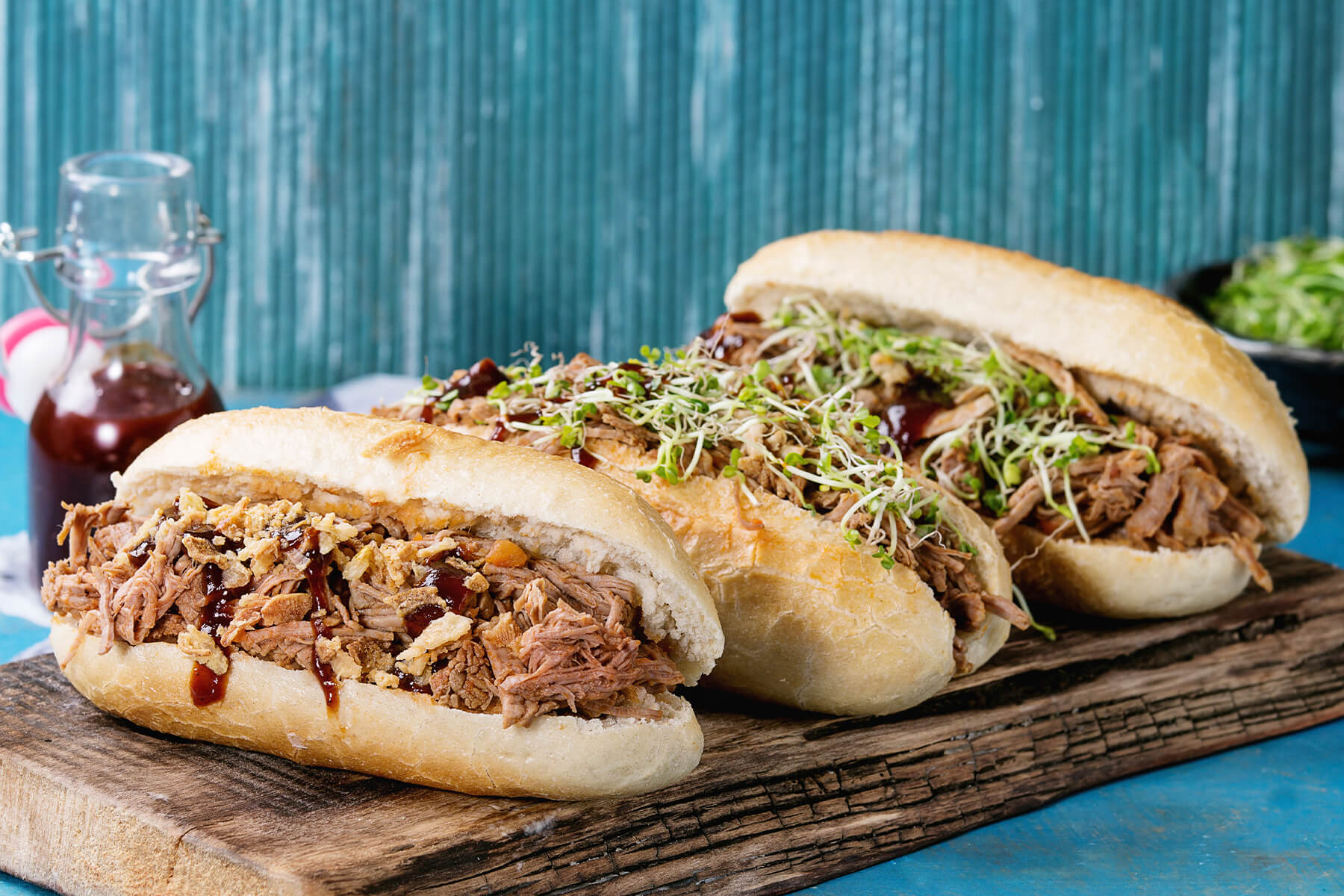 Drei Pulled Pork Subs mit verschiedenen Toppings auf einem Servierbrett
