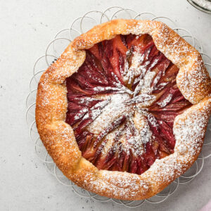 Rustikale Rhabarber-Galette mit Sternmuster aus roten Rhabarberstangen und gefaltetem Mürbeteigrand