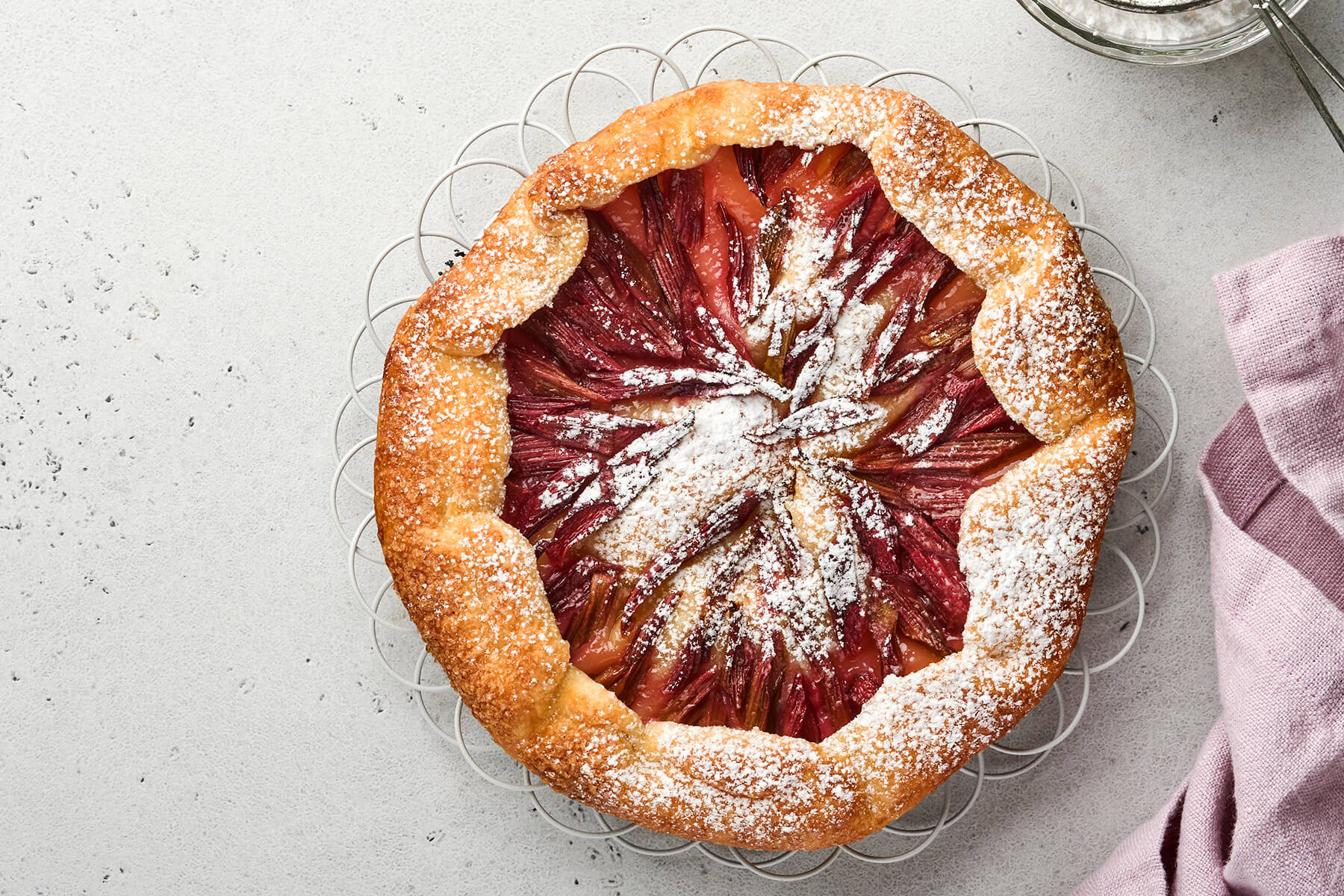 Rustikale Rhabarber-Galette mit Sternmuster aus roten Rhabarberstangen und gefaltetem Mürbeteigrand