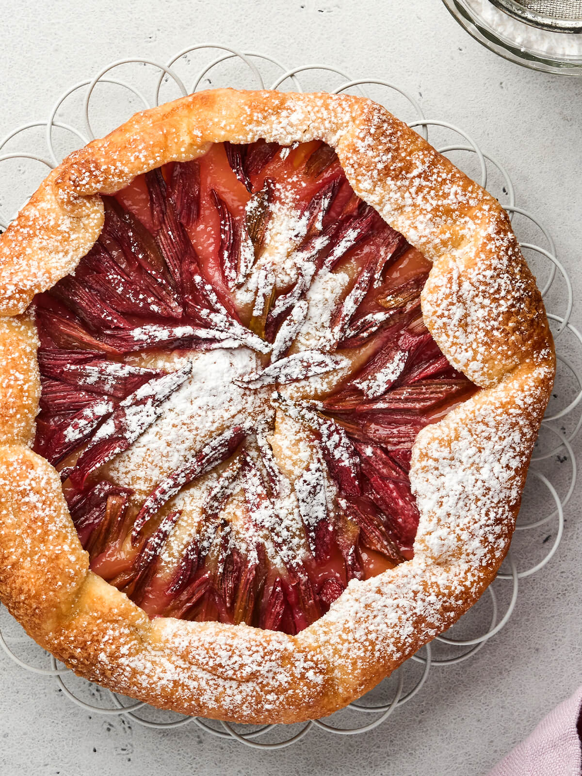 Rhabarber-Galette mit Sternmuster aus roten Rhabarberstangen, rustikalem Mürbeteigrand und Puderzucker
