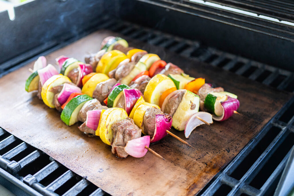 Rinder-Gemüse-Spieße beim Grillen auf der Grillmatte, das Fleisch bereits gebräunt