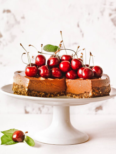 No-Bake Schoko-Cheesecake mit Kuppel aus frischen Kirschen und Minze auf weißer Tortenplatte