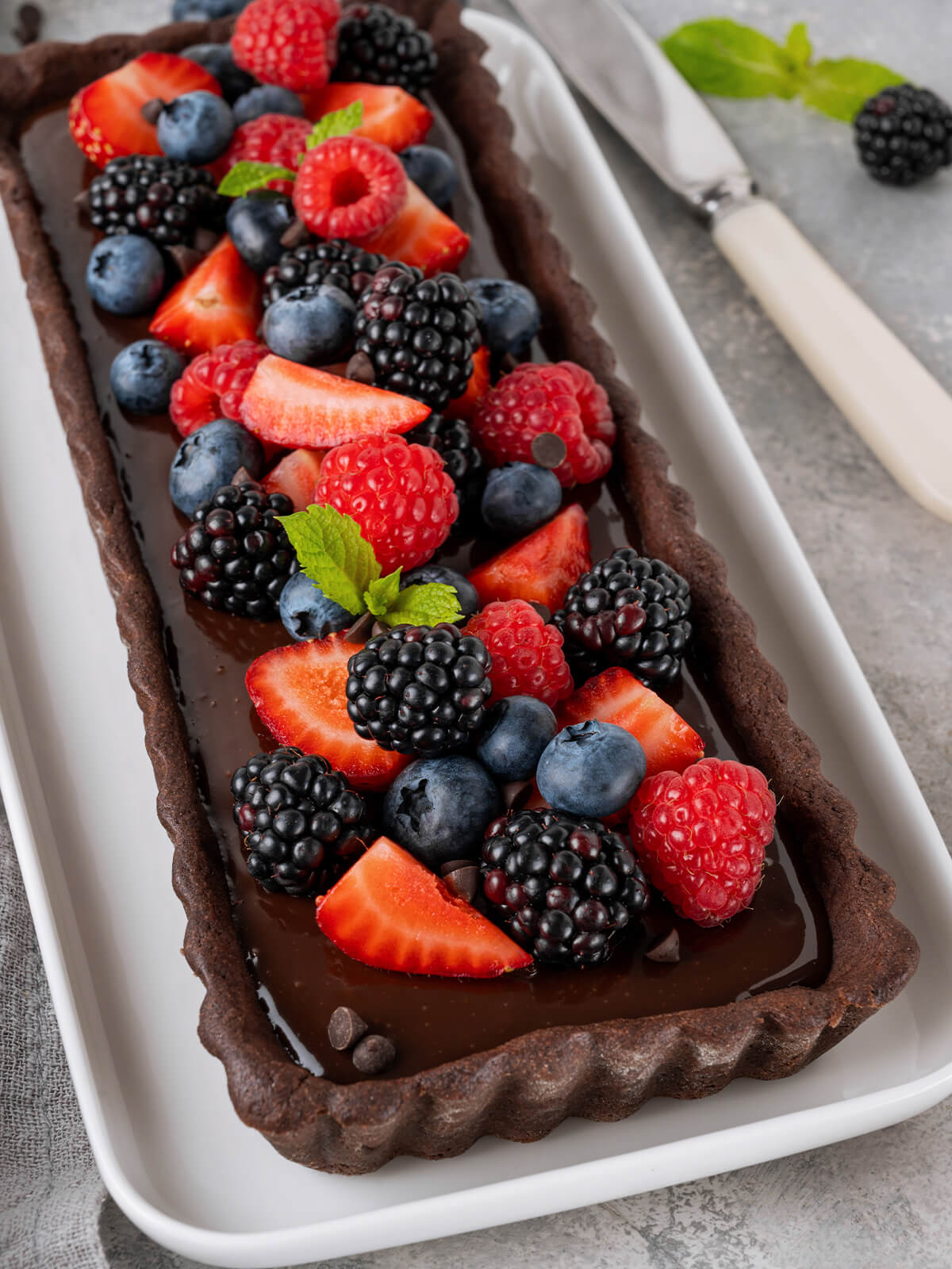 Rechteckige Schoko-Cream-Tarte mit gewelltem Mürbeteig-Rand und Beeren-Krone von der Seite