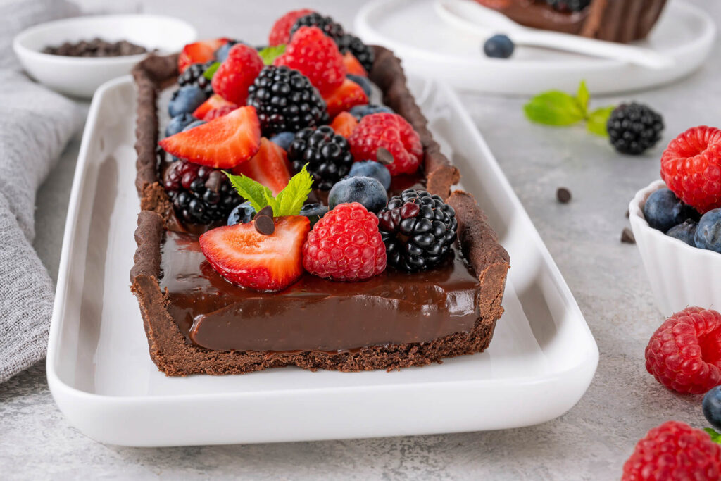 Angeschnittene Schoko-Cream-Tarte mit sichtbarer Ganache-Schicht und Mürbeteig-Boden im Querschnitt