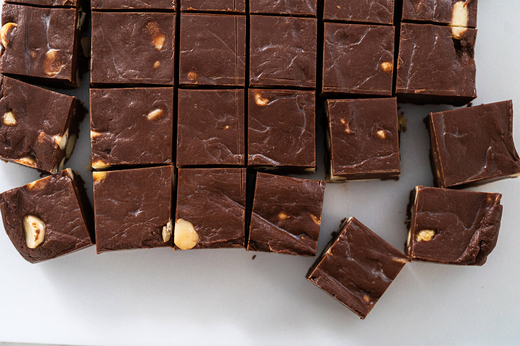 Schoko-Macadamia-Fudge-Block in gleichmäßige Streifen geschnitten auf einem hellen Teller