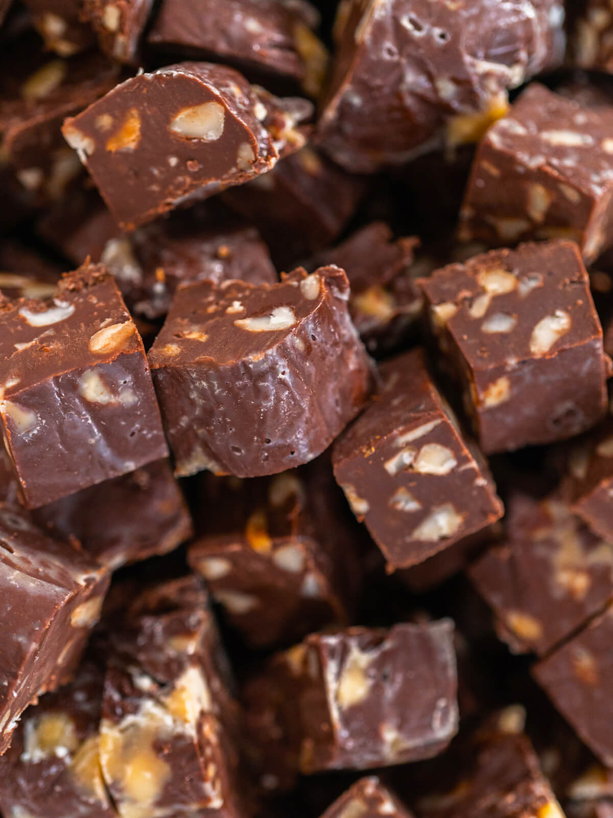 Aufgehäufte Schoko-Macadamia-Fudge-Würfel aus der Nähe, im Anschnitt sind die hellen Macadamia-Nüsse zu sehen