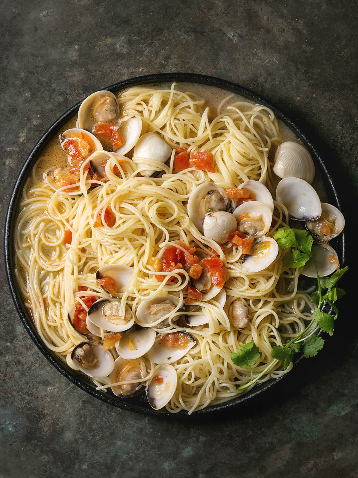 Spaghetti alle Vongole mit geöffneten Venusmuscheln und Tomatenwürfeln