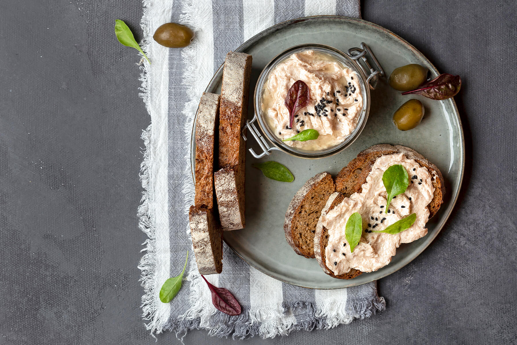 Thunfisch-Rillettes im Bügelglas mit dunklem Landbrot, grünen Oliven und schwarzem Sesam